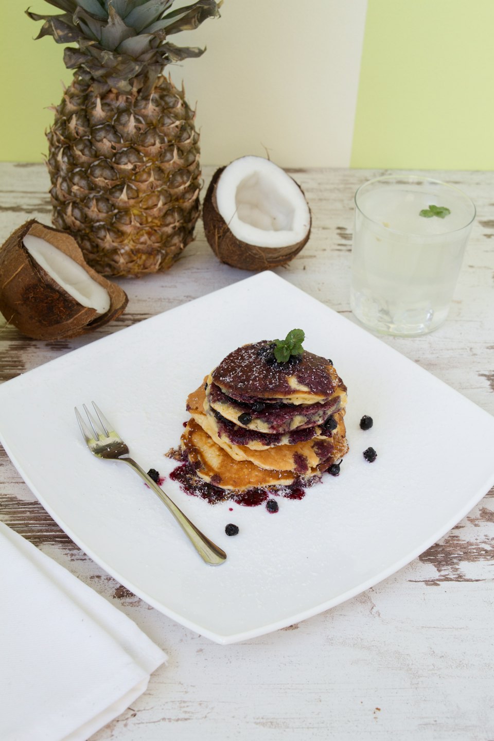 Fluffy blueberry pancakes with powdered sugar and mint on a plate.