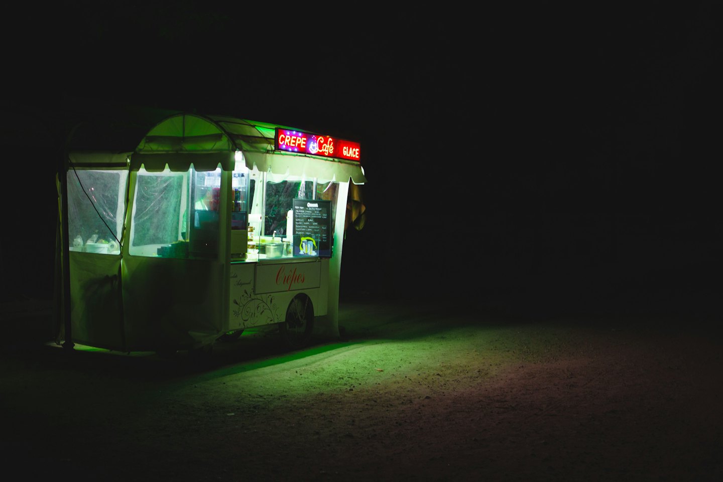 Mobile food cart serving crepes and coffee at night.